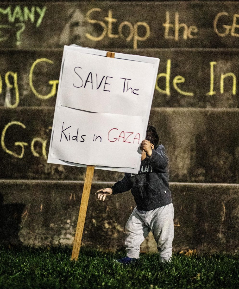 Esraa Jarrars child picks up a sign saying, Save the kids in Gaza at the vigil for the children in Gaza who have been killed. 