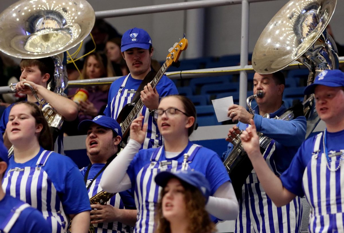University President Jay Gatrell reads sheet music and plays while members of Panther Pep Band  dance and shout during the Panther War Chant during the womens basketball game against Western Illinois University at Groniger Arena on Saturday afternoon. Gatrell joined students in playing Easterns Panther War Chant and Alma Mater For Us Arose.