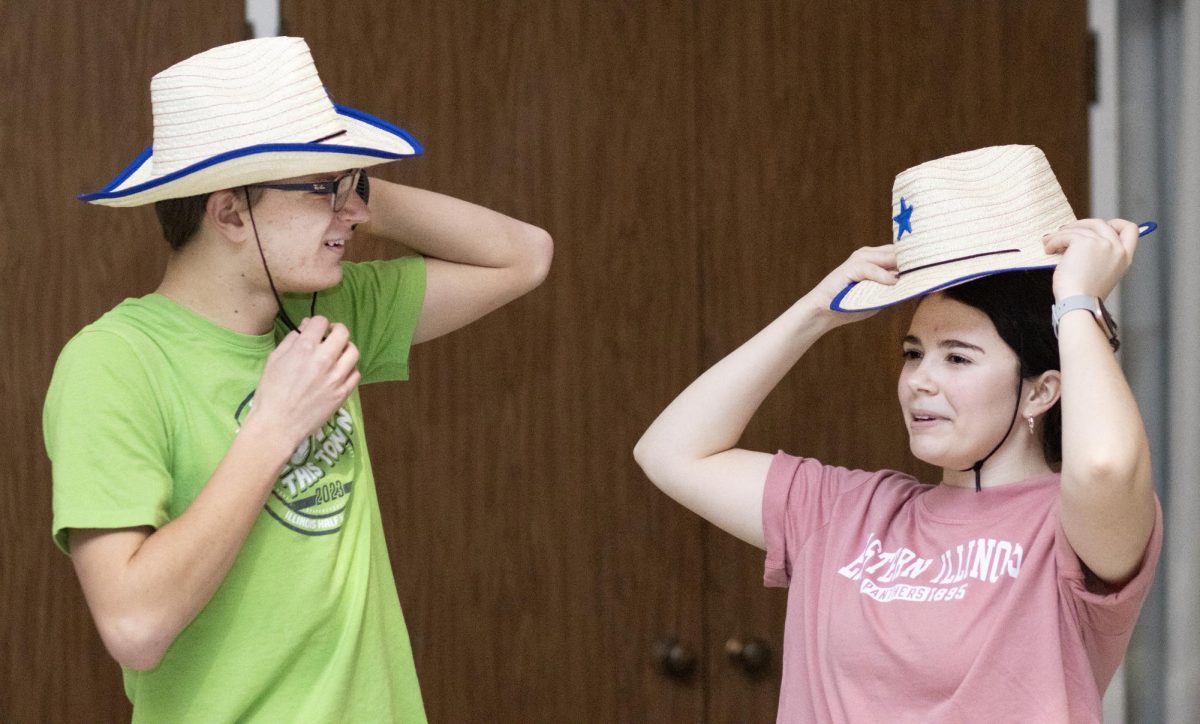 From left, sophomore Dylan Meek, and sophomore Rachel Wisner get ready to join the fun by putting on cowboy hats at the Panther Ho-Down event hosted by The Underground Line Dancing club on Saturday evening.