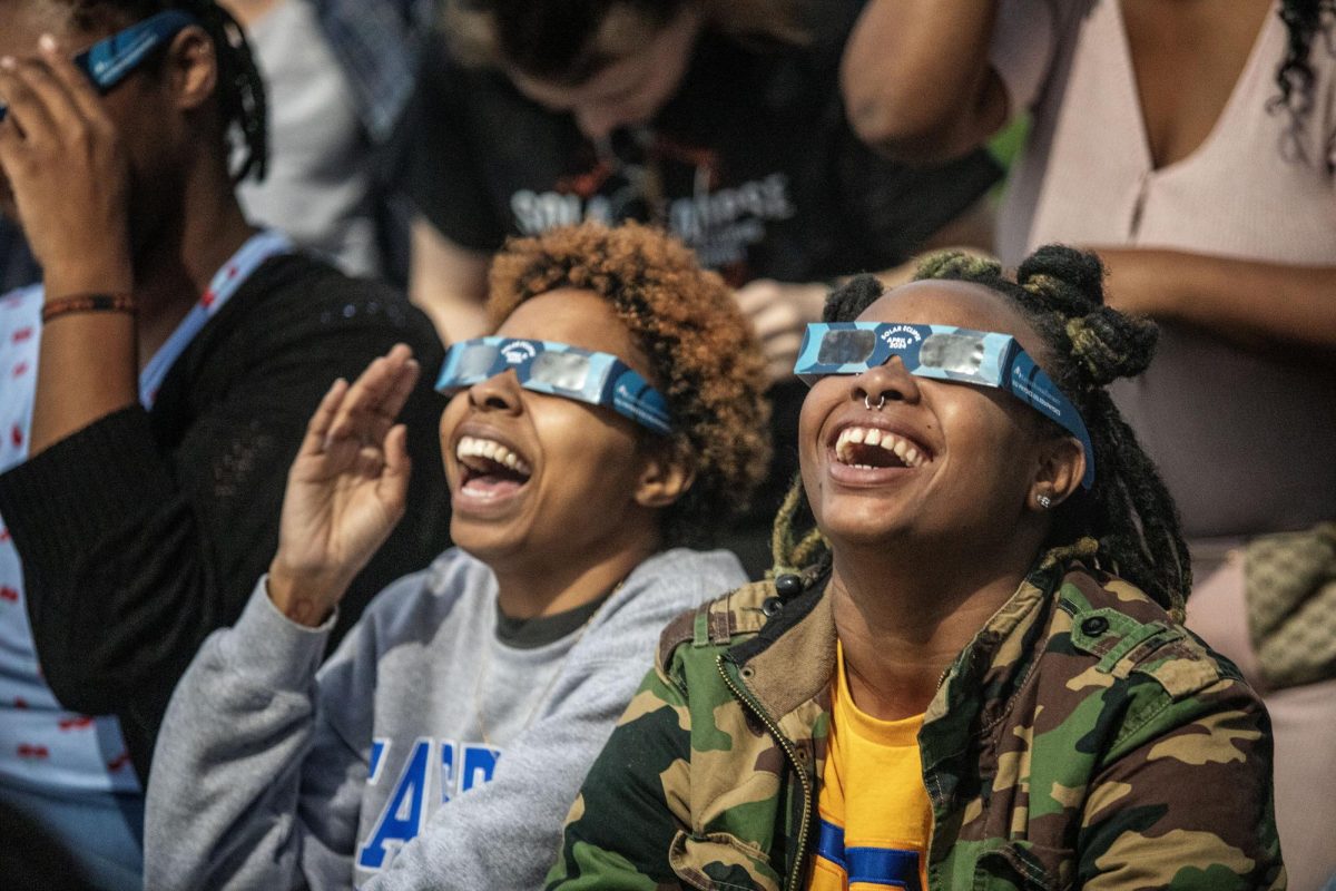 From right, Shay Edmond, a senior sociology major, and Brianna Hull-Dennis, a senior political science major, watch the solar eclipse with friends Monday afternoon at the campus observatory. Edmond said the turnout made the viewing much more exciting. 