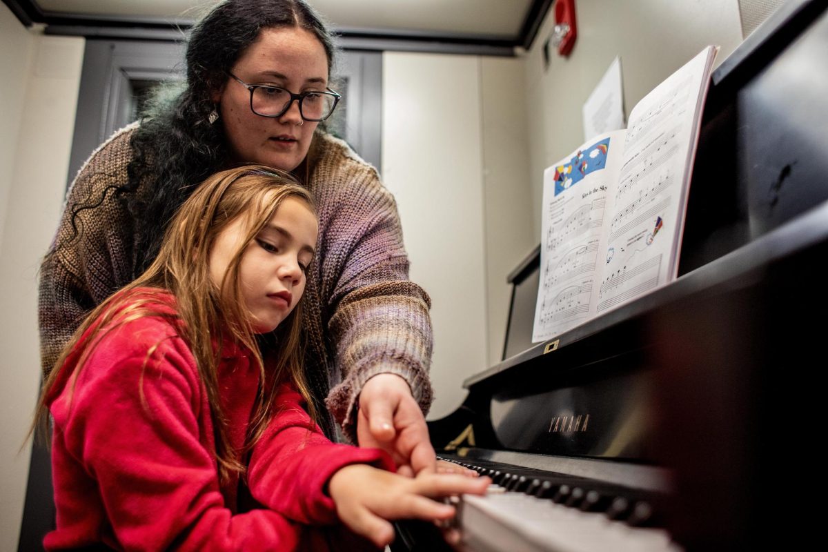 Jemma Allen, a junior vocal performance and music education major, instructs Madison More, 8, a student at Carl Sandburg Elementary School, on which notes to play on the piano in a practice room in the basement of the Doudna Fine Arts Center Thursday. 