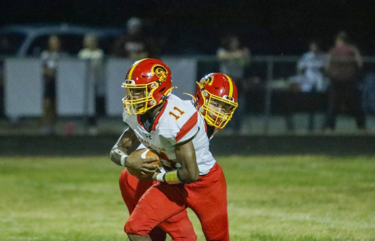 Charleston High School junior running back Treylin Couch receives a handoff from junior quarterback Wyatt Gordon in the Trojans opening game of the 2025 season as Charleston went on to lose 41-6 to Robinson at Crosby Field on Friday.