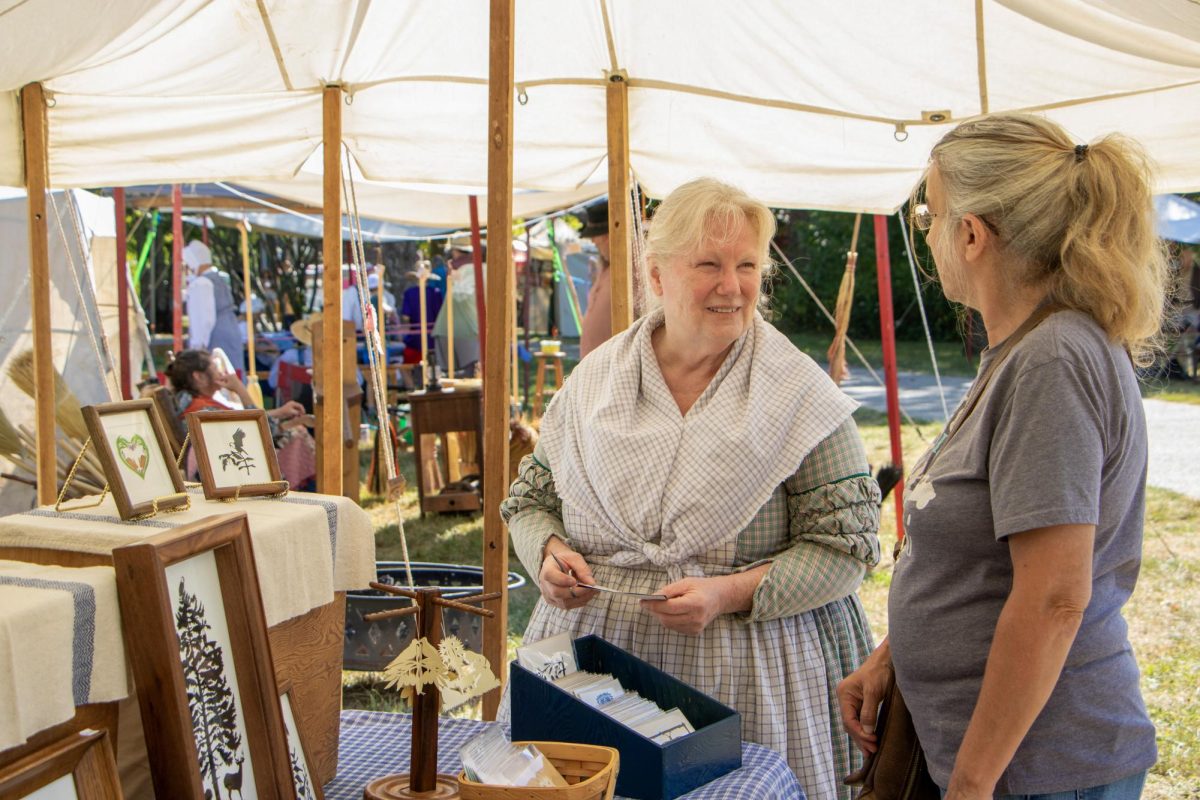 Papercutter Barbara Dyar (Left) explains to Mattoon native Kathy Dean (Right) how she makes her art at Harvest Frolic. Dyar said she specializes in black and white cuttings depicting Illinois wildlife.
