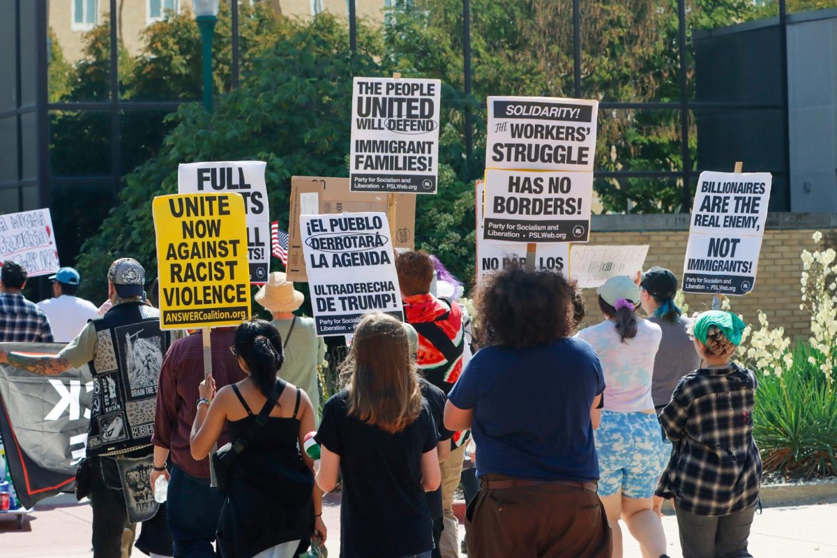 People at the Students for Socialism Anti-ICE protest walk past EIU's Biology building as they protest against ICE on Sunday.