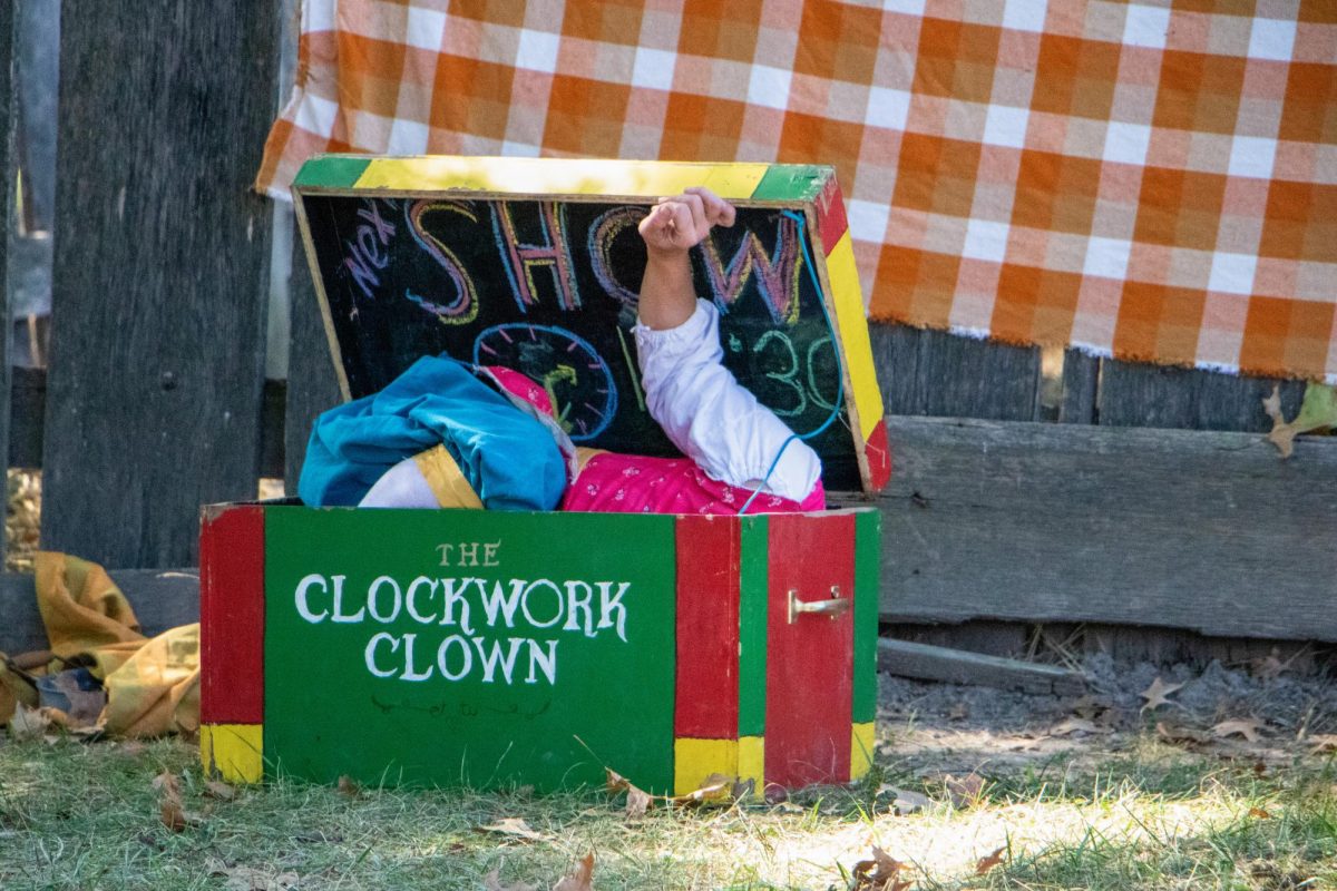 Emerald Kelley as the Clockwork Clown folds herself into a small box and closes the lid.