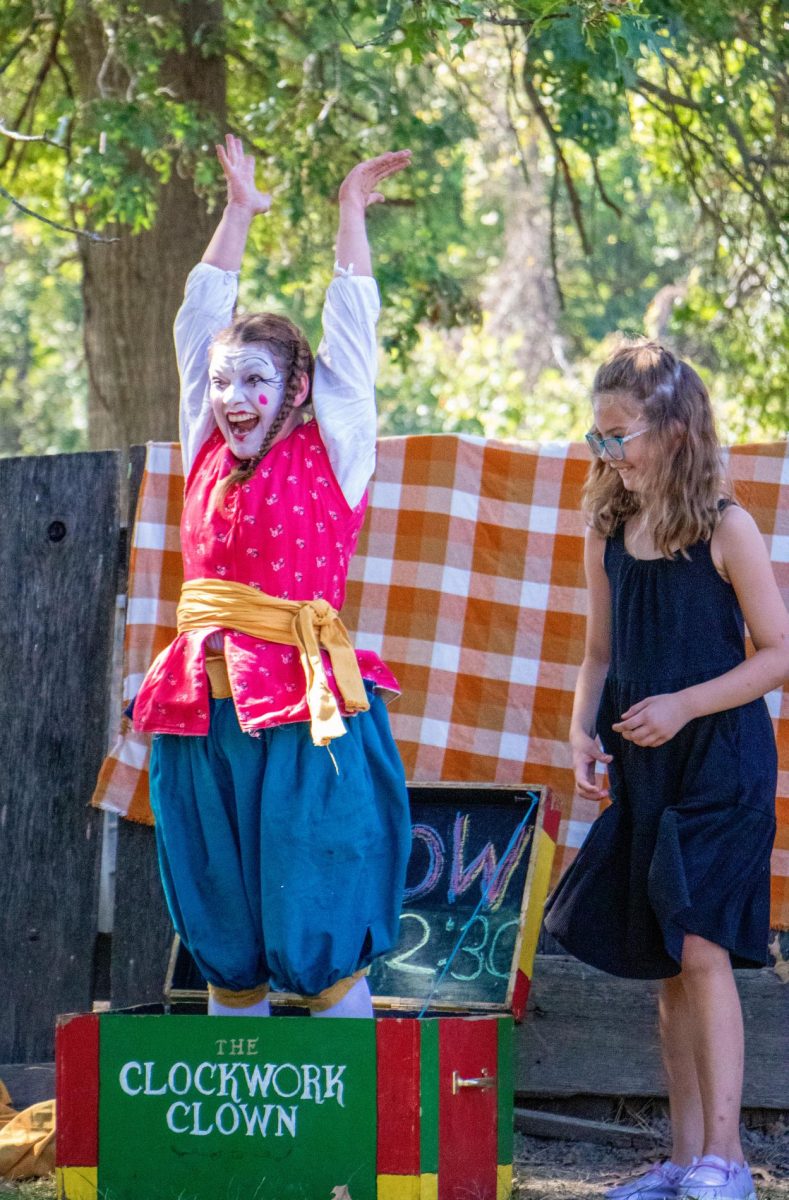 Clockwork Clown Emerald Kelley (Left) pops out of the box she was folded as 9-year-old audience volunteer Briella Walters (Right) smiles and claps excitedly.