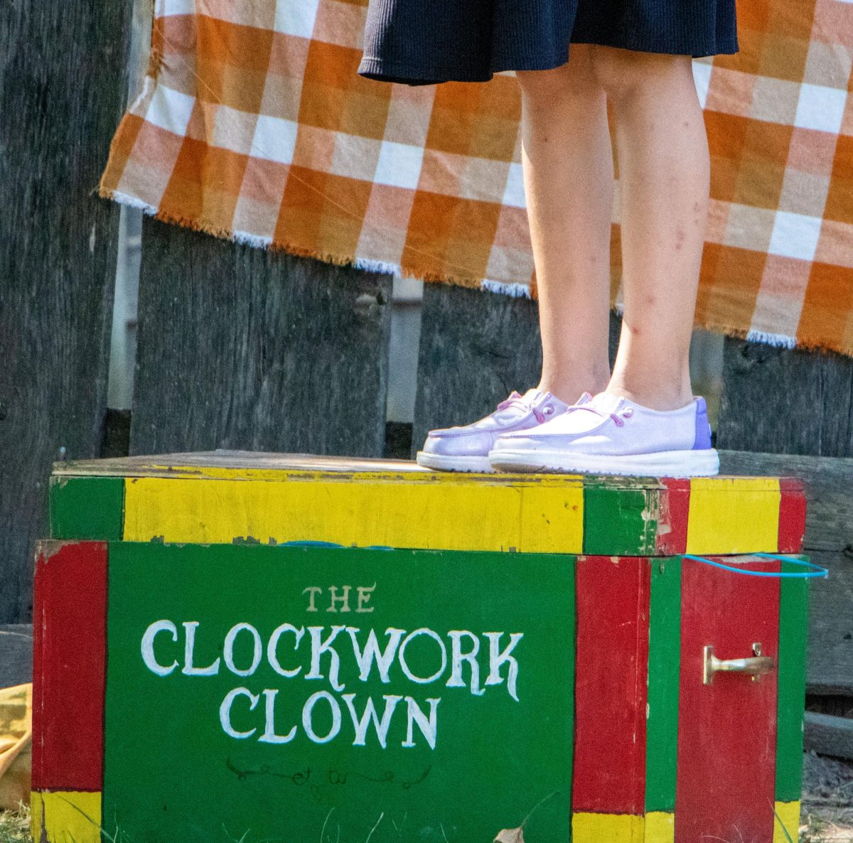 Nine-year-old audience volunteer Briella Walters stands on the box containing Clockwork Clown Emerald Kelley to keep the lid closed at Harvest Frolic on Sept. 28.