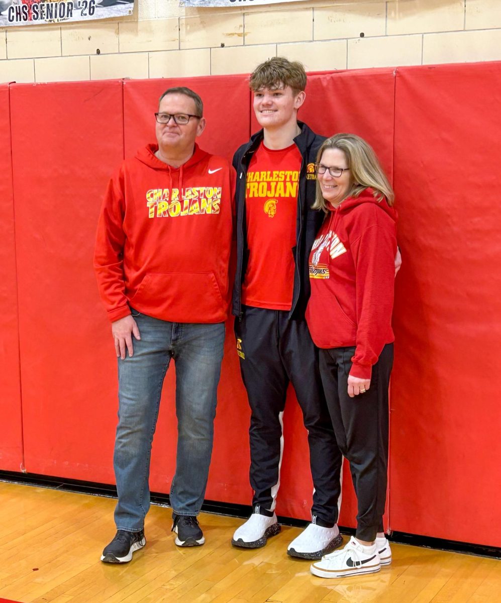 Charleston High School senior guard Tyler Oakley (center) poses for photos with his parents, Brad (left) and Debbie (right) Oakley, after Tyler broke the Charleston basketball scoring record against Effingham at Charleston High School on Friday.