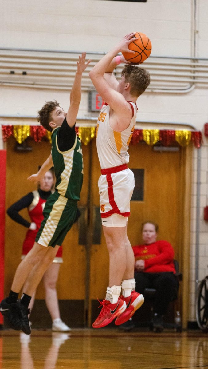 Charleston High School senior forward Tyler Oakley shoots a 3-point shot over Mattoon High School sophomore guard Maxwell Wetzel during the Trojans 66-32 loss to Mattoon Tuesday night at Baker Gym.