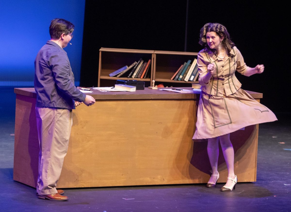 Margo played by Olivia Enlow dances away from Billy Cane played by Gentry Copsy after hugging him when Billy Cane visits Margo at her bookstore in Bright Star. Bright Star occurred from Friday, Feb. 27, 2026 until Sunday, March 8, 2026 in Doudna Fine Arts Center.