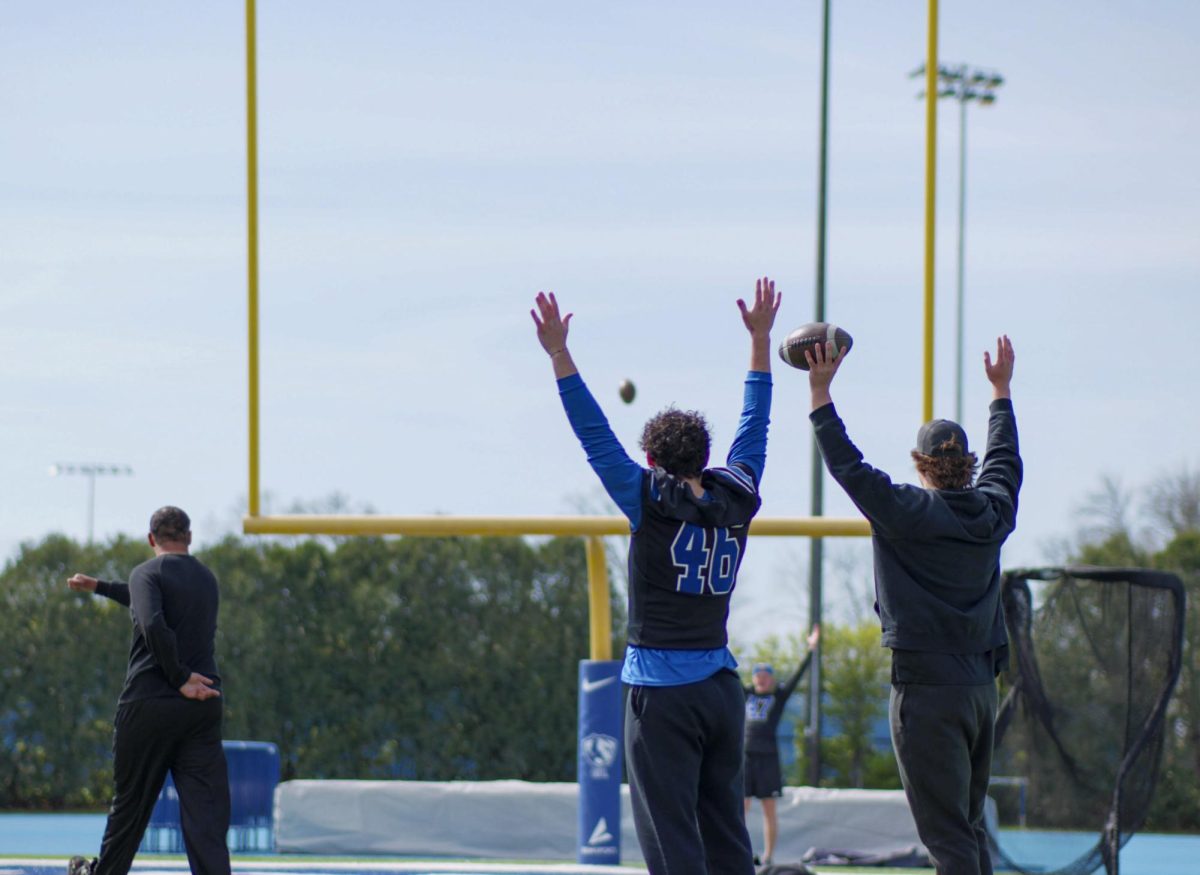 Zach Baillie, a participant of the Beautiful Lives project, kicks a ball through the uprights behind the south end zone of O'Brien Field while EIU football players cheer on Wednesday.