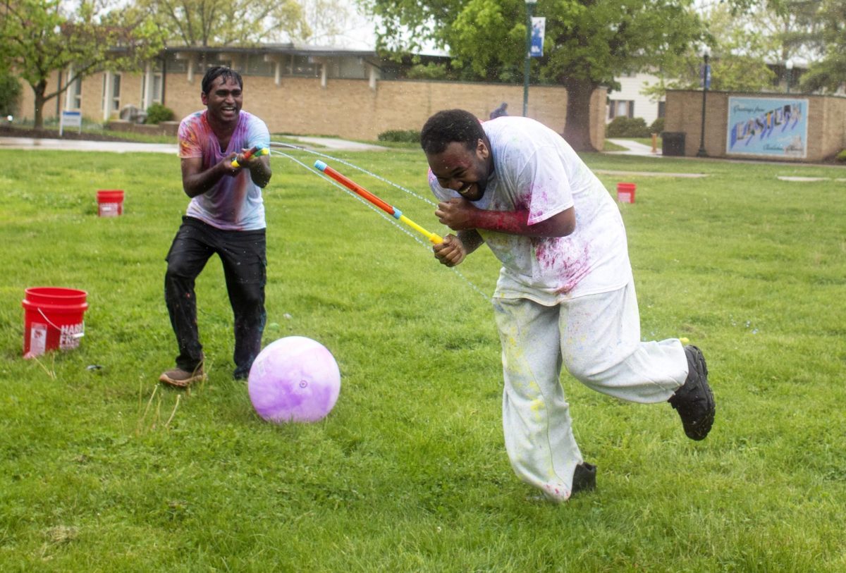 Technology major Krishna Daravath (left) sprays hospitality entrepreneurship major Terrell Steele (right) with a water toy at Holi Color Fest on Friday on the Library Quad.