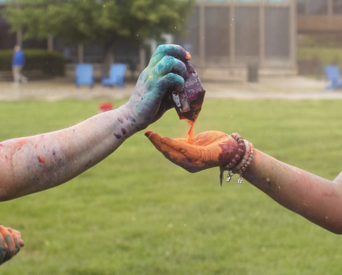 Austin Van Tise (left) puts pigment into Vani Patel's (right) hand at Holi Color Fest on Friday on the Library Quad. Van Tise and Patel would begin to throw pigment at each other.