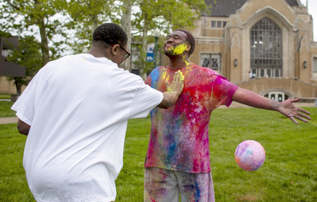 Art education major, Josiah Nesbitt (left) puts pigment onto hospitality entrepreneurship major Terrell Steele (right) at Holi Color Fest on Friday on the Library Quad.