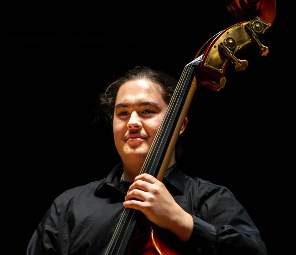 Eastern Illinois University junior music education major Race Brighton smiles while holding a double bass as the crowd applauds after the EIU Faculty Chamber Concert at the Doudna Recital Hall on Monday night.