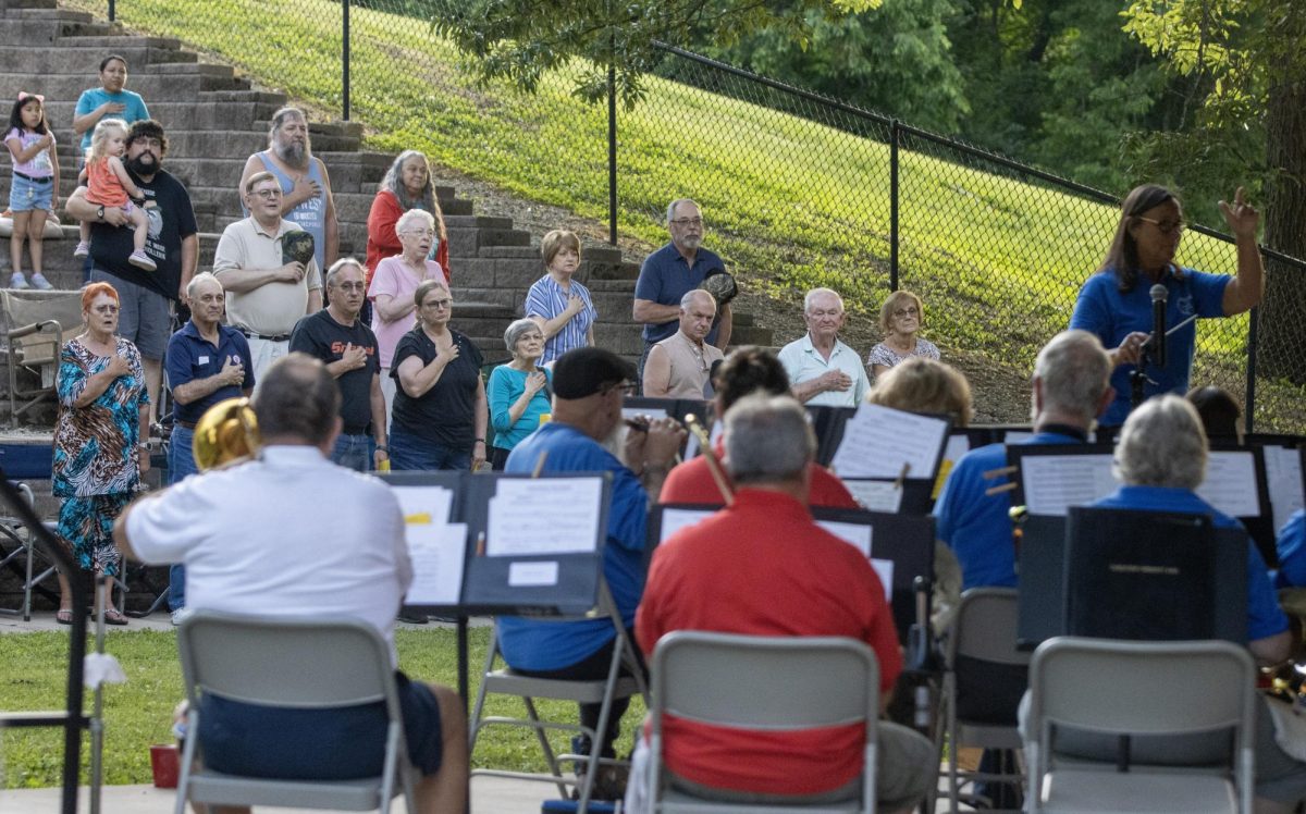 The audience for the Charleston Community Band stands as the band plays the National Anthem to start its weekly performance at Kiwanis Park on Thursday.