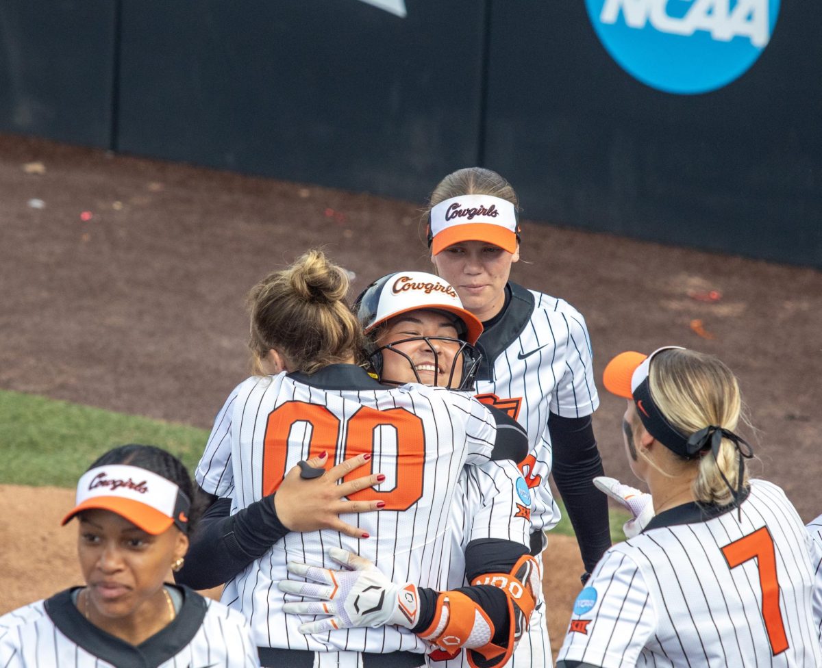 Oklahoma State University softball freshman pitcher Makala Smith (left) hugs her teammate, senior catcher Amanda Hasler (right) after Hasler’s home run during EIU’s 16-0 loss to Oklahoma State University in the second game of the NCAA Stillwater Regional on Friday.
