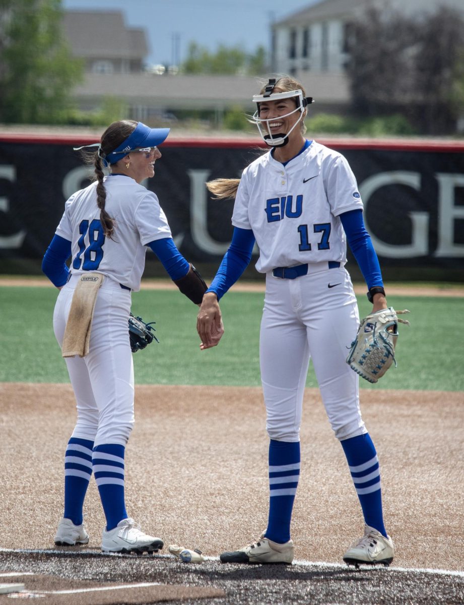 Eastern Illinois University softball junior infielder Chloe Wamboldt (left) high-fives and laughs with senior pitcher Karlie McKenzie (right) during its 7-6 win against Southeast Missouri State in the first round of the Ohio Valley Conference tournament at OSF Healthcare Field.
