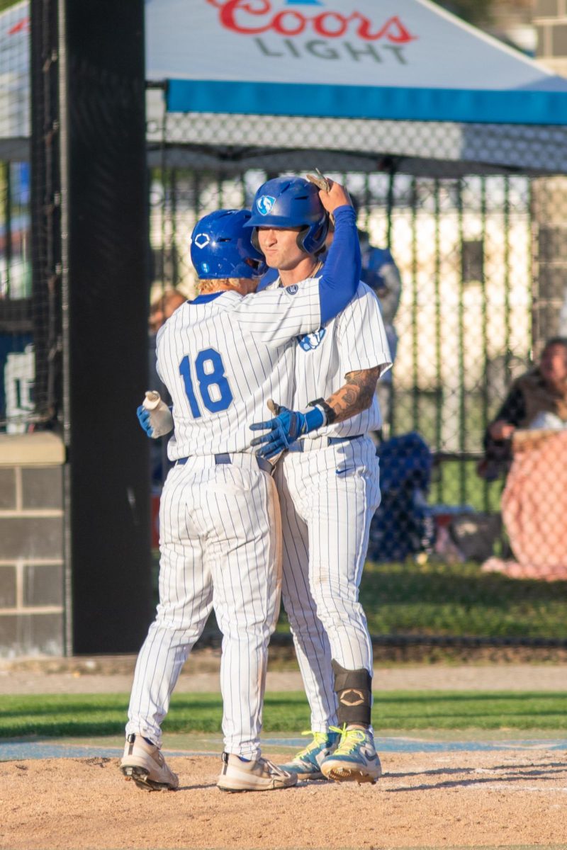 Graduate student Chris Worcester (left) hugs sophomore infielder James Love (right) after scoring during EIU baseball's win over SEMO at Frost Field on Saturday.