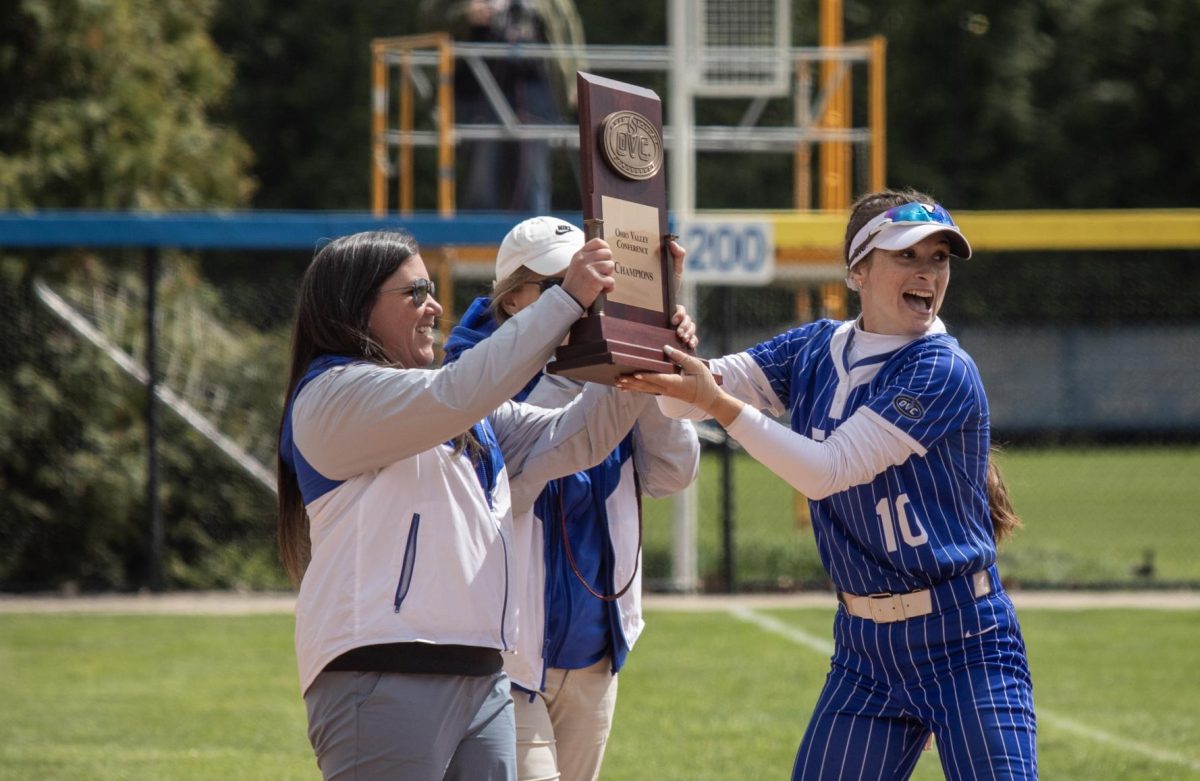(Thumb) Eastern Illinois University softball junior Sophia Olman (right) takes the Ohio Valley Conference trophy from Assistant Athletic Director Amber May (left) after EIU’s 15-0 win over Tennessee State University at Williams field on Saturday.